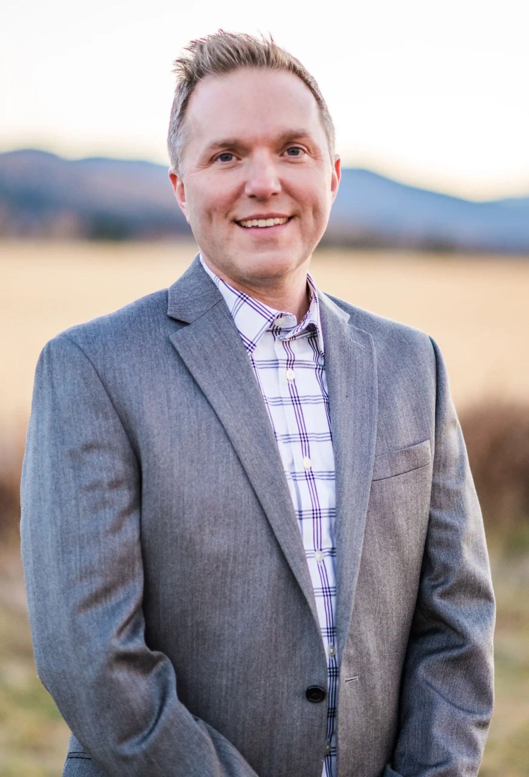 Professional headshot of man in gray blazer outdoors