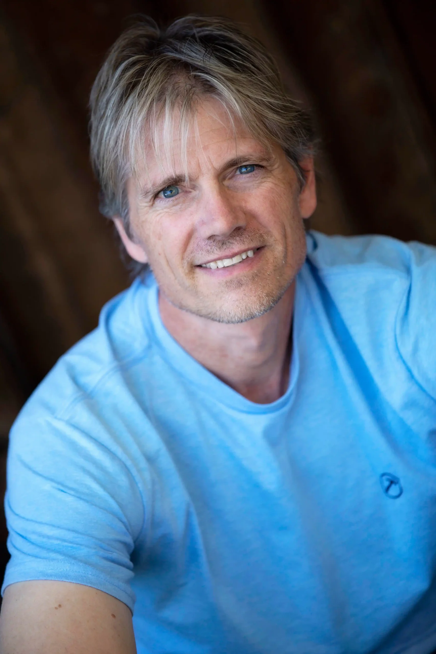 Professional headshot of man in blue shirt smiling