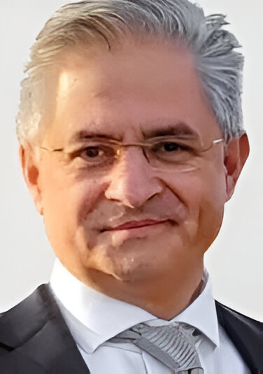 Professional headshot of older man in suit smiling